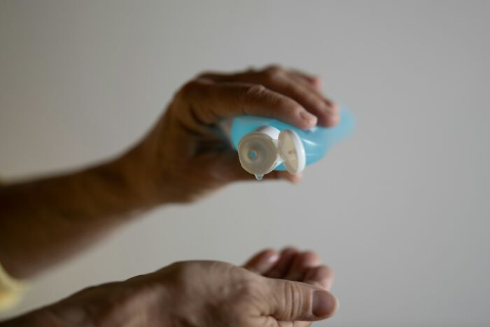 Hands squeezing blue hand sanitizer into a palm, demonstrating common poverty habits.