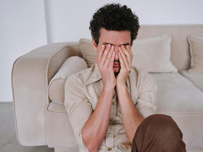 A man with curly hair covering his face, appearing stressed over MIL, DIL's pettiness and coffee order.