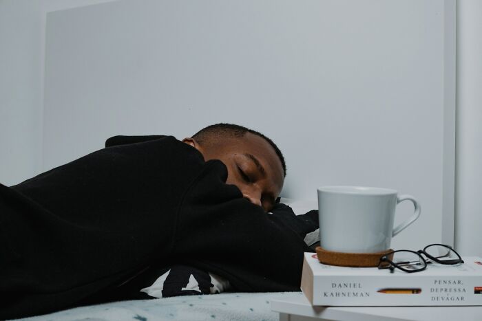 A man sleeps soundly in bed with a book and mug nearby, depicting stories about life and what comes after.