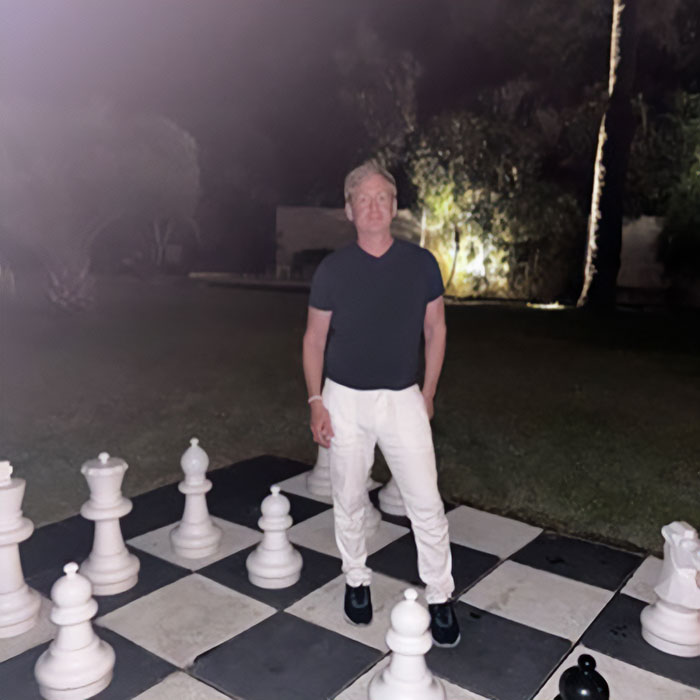 CEO who went viral for firing 900 employees stands on a giant chessboard at night.