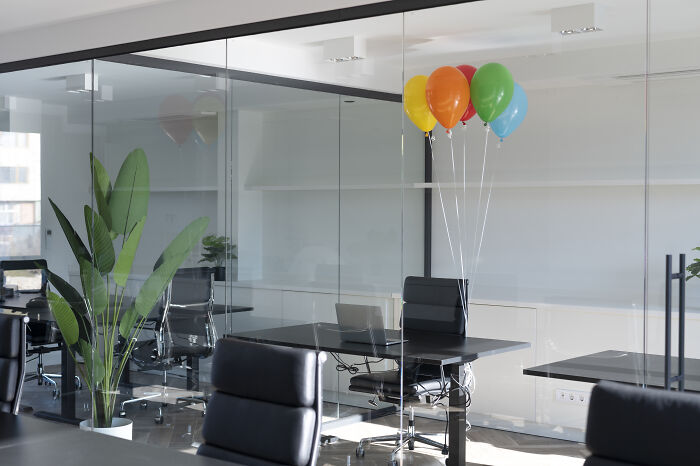 An empty office space with colorful balloons, representing the quiet before or after work drama unfolds.