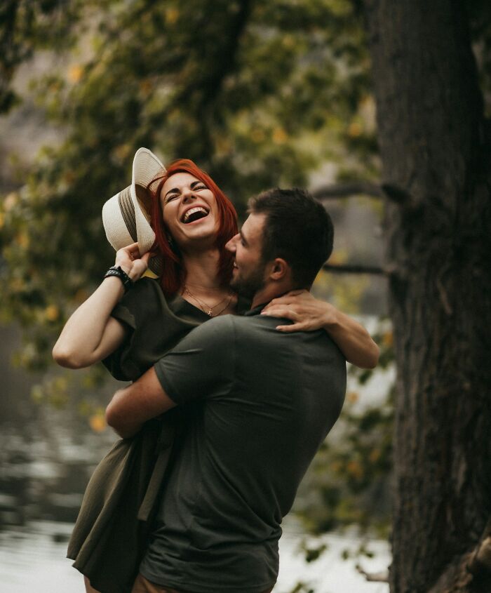 A happy, married couple embraces and laughs outdoors near a tree, showing the joyful truths of being married.