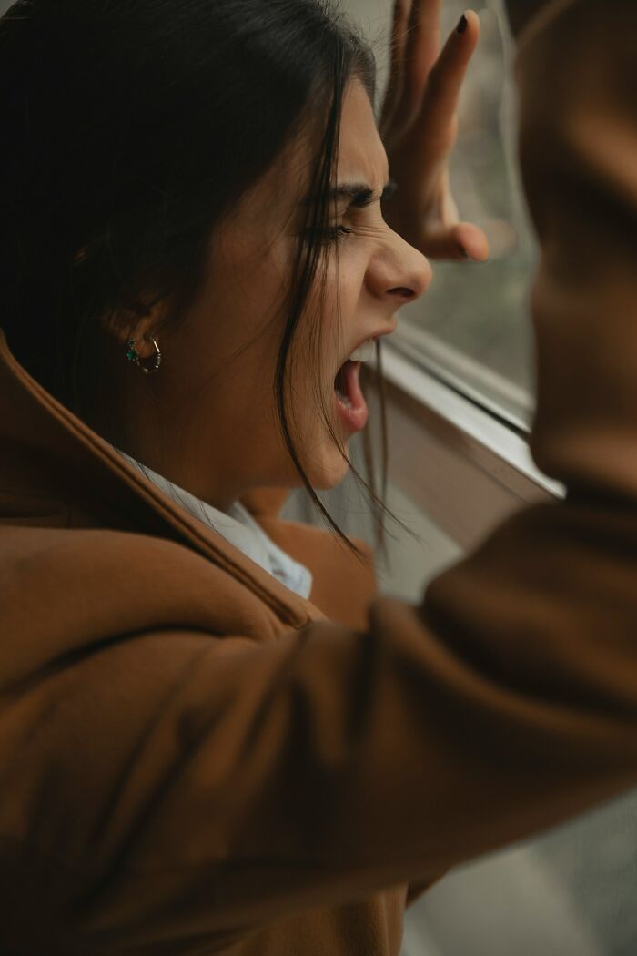 A woman screaming out a window, expressing anger or frustration. Reflects interesting neighbors.