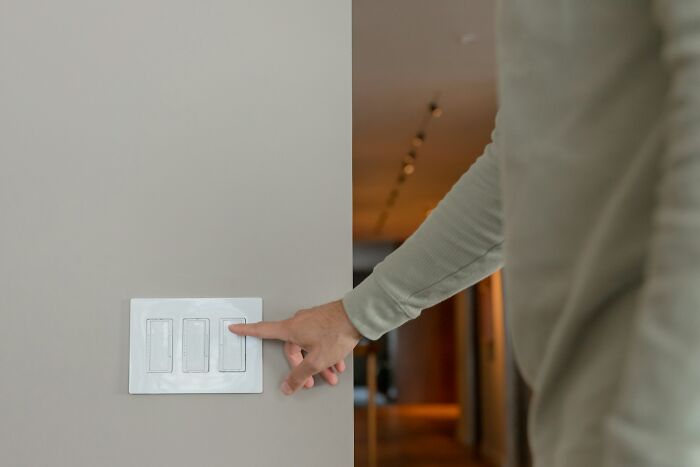 A person turning off a light switch, demonstrating one of the poverty habits that save money.