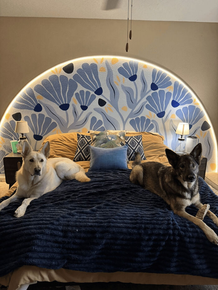 Two dogs on a bed with a vibrant floral DIY home project headboard, showcasing a transformed space with a budget-friendly design.