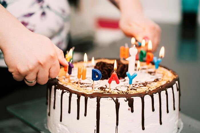 Lighting candles spelling B-I-R-T-H-D-A-Y on a cake for work drama stories.