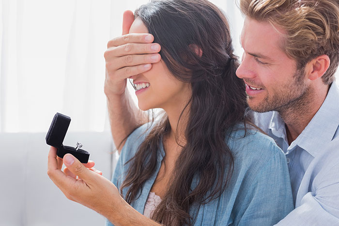 A man proposes to a woman with a ring, covering her eyes for a surprise wedding proposal. A man proposes to a woman with a ring, covering her eyes for a surprise wedding proposal.