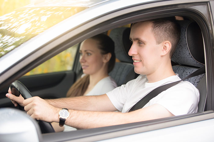 A BF and female friend or coworker are smiling while driving in a car.