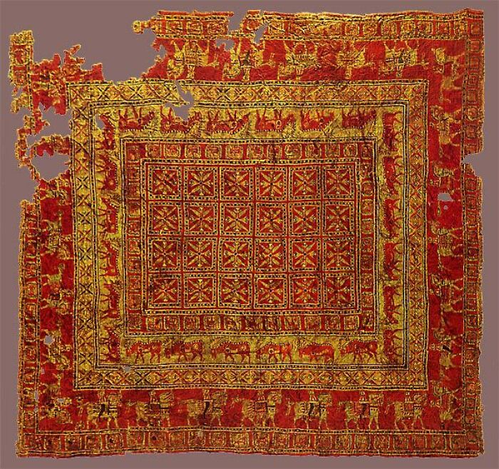 A detailed ancient red and gold patterned rug, historical artifact, showing intricate designs and preserved textile art.