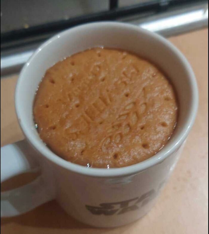 A biscuit perfectly fitting inside a mug, showcasing dry British humor.
