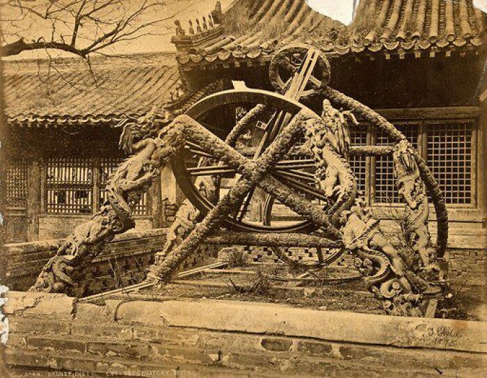 An old photograph showing an intricate bronze astronomical instrument, historical artifact, with dragon motifs and ancient architecture.