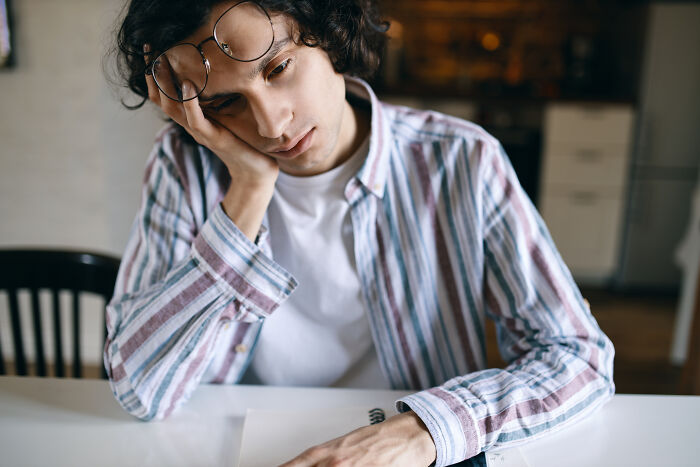 A man looking dejected at a table, reflecting the emotional toll of being raised by narcissists.