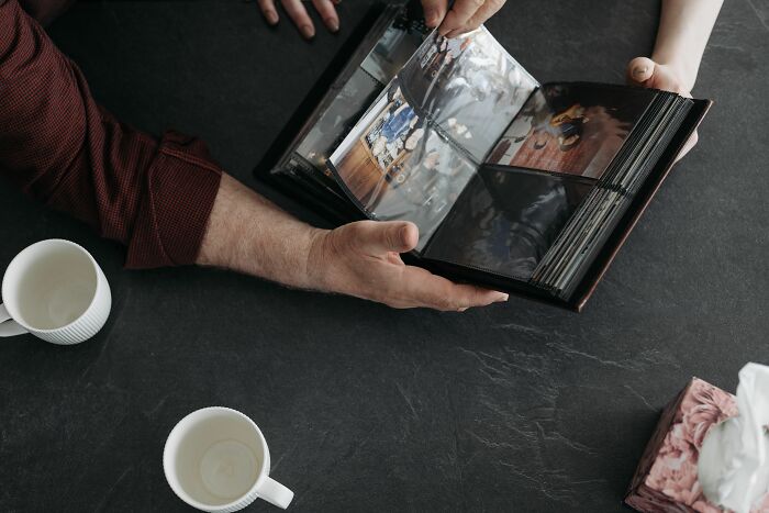 Hands turning pages of a photo album, remembering a childhood and the impact of being raised by narcissists.