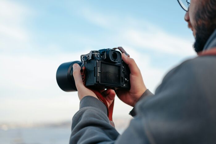 A person with a camera, looking out over a view, thinking about being raised by narcissists and their painful stories.