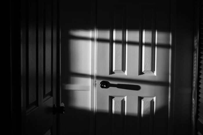 Scariest things witnessed: A dark shadow of a key or handle is cast on a closed door, creating an eerie atmosphere.