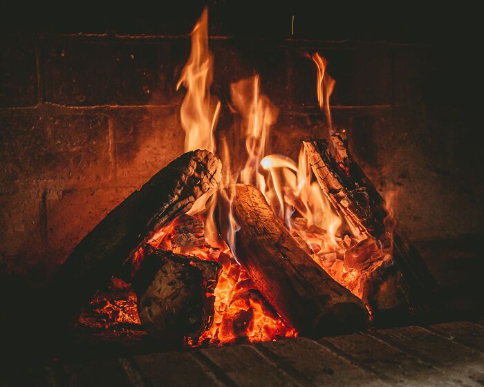 A fireplace with burning logs and glowing embers, a scariest thing to witness, providing warmth.