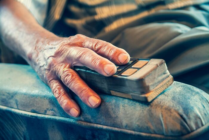 A close-up of an elderly hand resting on a remote control, depicting the scariest things witnessed at home.