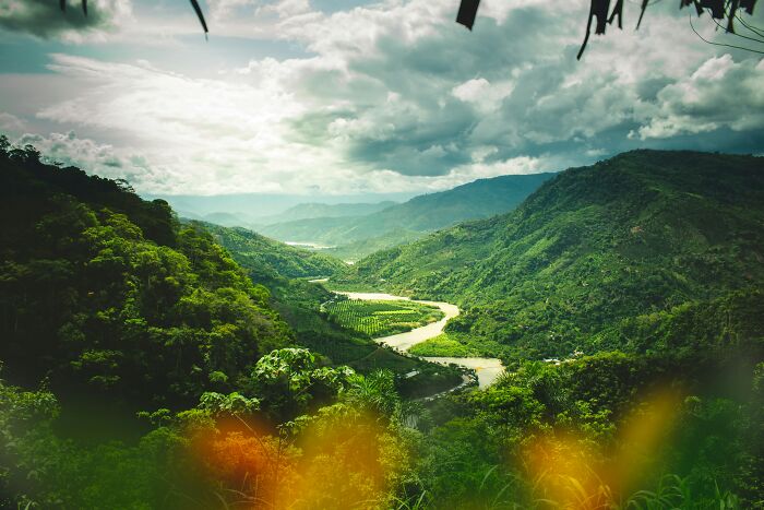 A winding river through a lush green valley under a cloudy sky. This image evokes scariest things people witness.