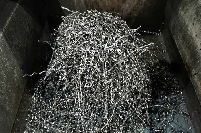 A pile of metal shavings, a scariest thing to witness, twisted and spiraling, inside a dark container.