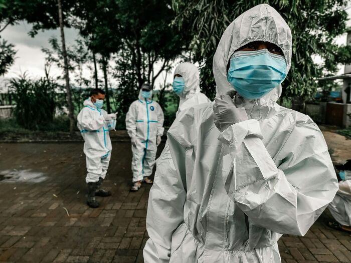 Healthcare workers in PPE suits and masks, a scariest thing to witness, stand outdoors.
