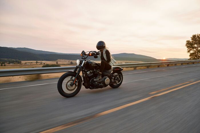 A person riding a motorcycle on a scenic road at sunset, reflecting on scariest things witnessed while traveling.