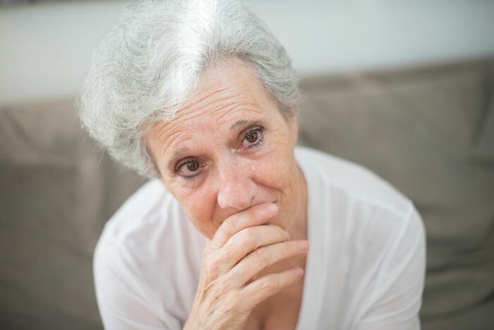 An elderly woman crying, looking directly at the camera. This image evokes scariest things people witness.