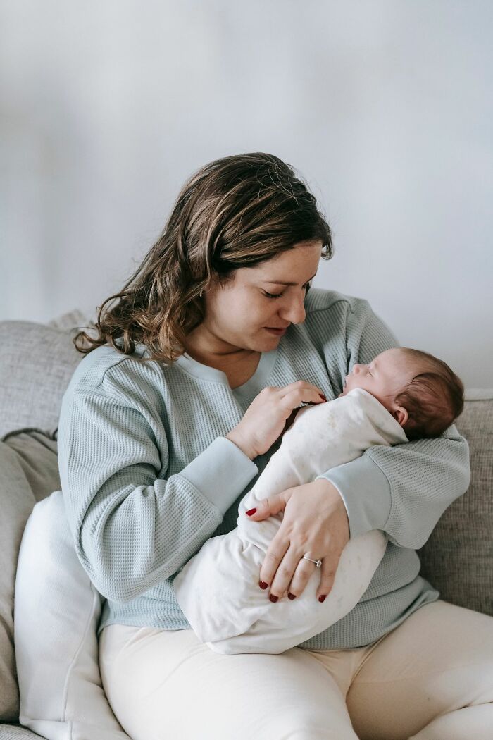 Woman gently holding a swaddled baby, a tender image contrasting discussions of toxic femininity and gender roles.