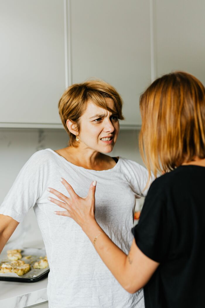 Two women arguing heatedly in a kitchen, showcasing a confrontational example of toxic femininity.