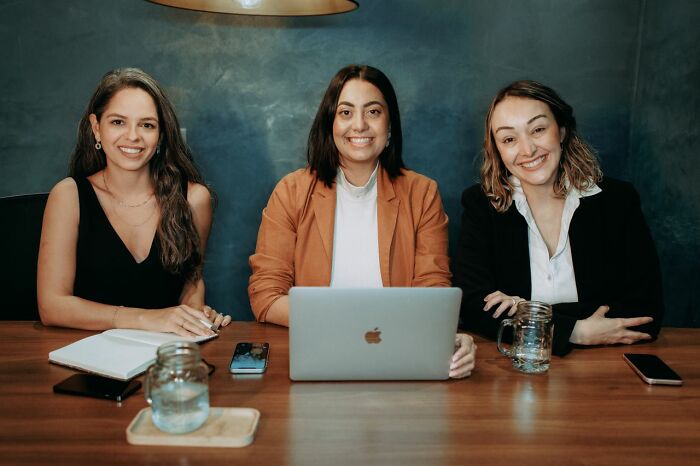 Three women smiling and looking at the camera, exemplifying different gender roles and toxic femininity.