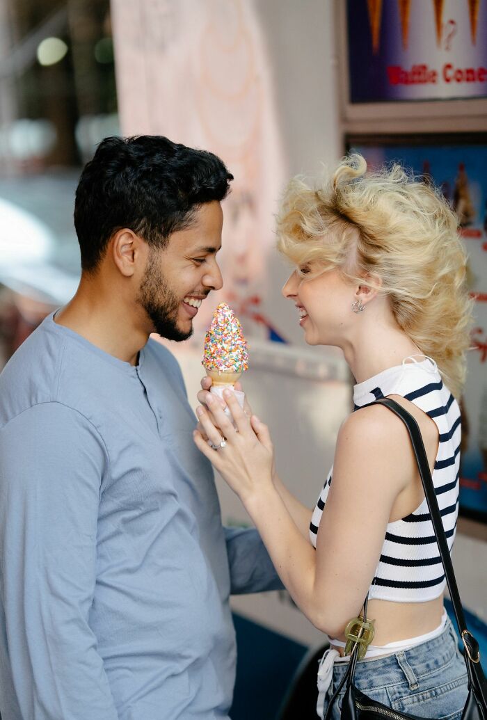 A couple smiling and sharing an ice cream cone, suggesting complex gender roles.