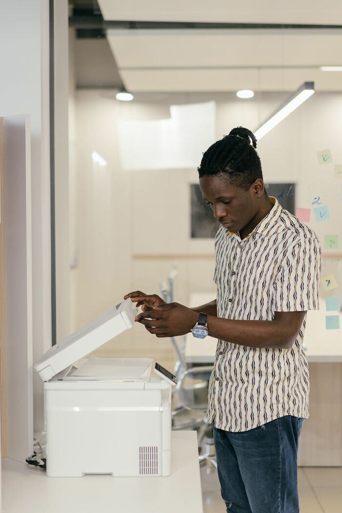 A man uses a printer in an office, subtly touching on societal gender roles and toxic femininity.