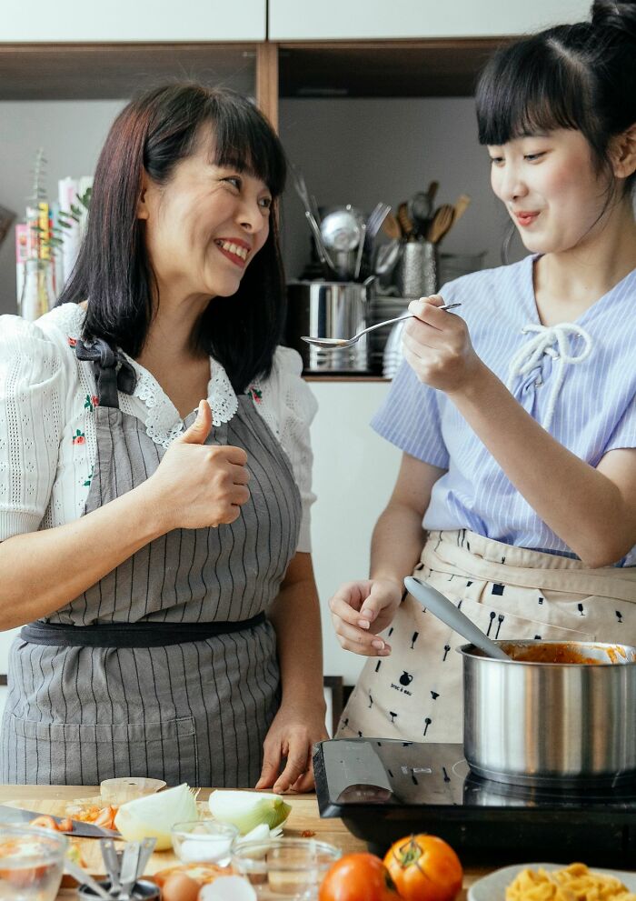 Two women smiling in a kitchen, showcasing a positive interaction amidst discussions of toxic femininity and gender roles.
