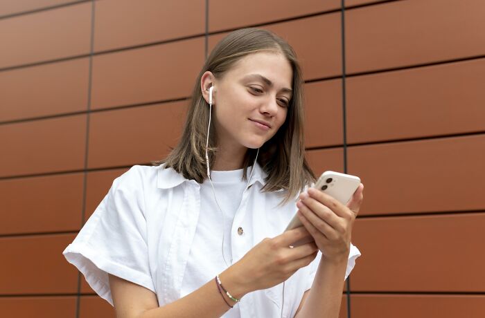 A young woman listens to music on her phone, possibly about to discover her partner's affairs in a brutal way.