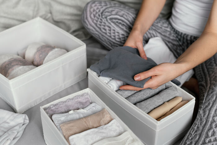 Hands folding clothes into storage boxes, possibly finding evidence of partner's affairs coming to light.