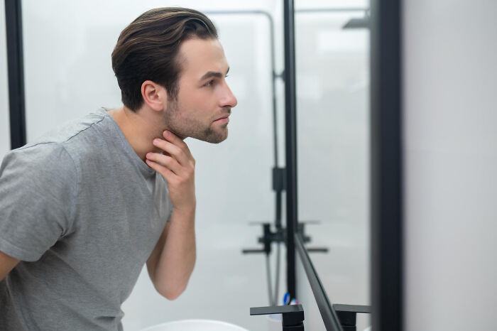 Man checking his reflection in a bathroom mirror. Affairs can come to light in brutal ways for partners.