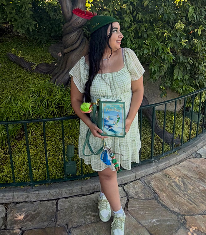 The Peter Pan girl smiles while holding a Peter Pan themed bag, displaying her decade-long Peter Pan obsession.