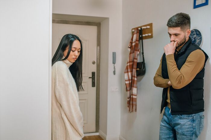 A woman stands apart from a man with a beard, both looking unhappy, realizing they're with the wrong person.