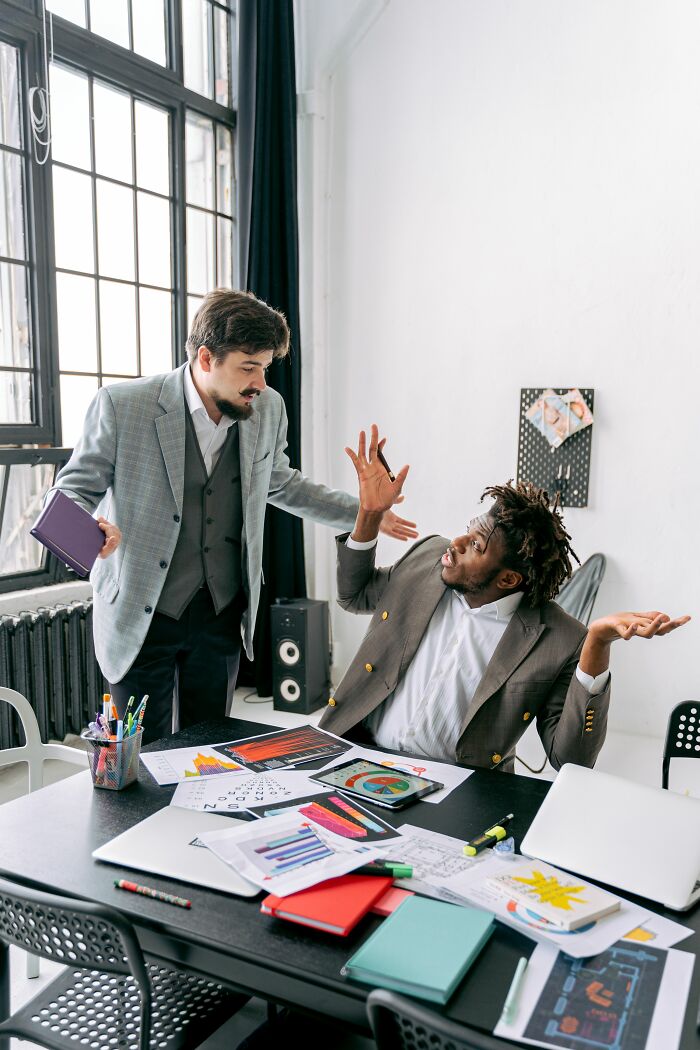 Two men in an office, one gesturing dramatically, earning mad respect for sick burns.