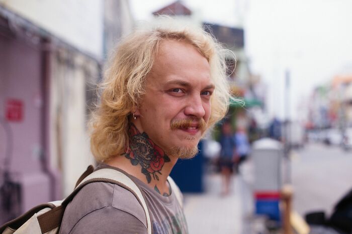 A man with blonde hair and a beard, smiling at the camera, showing a neck tattoo, related to misconceptions.