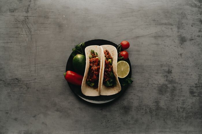 A pair of delicious-looking tacos with fresh ingredients on a plate, representing the diverse orders customers make at a drive-through.