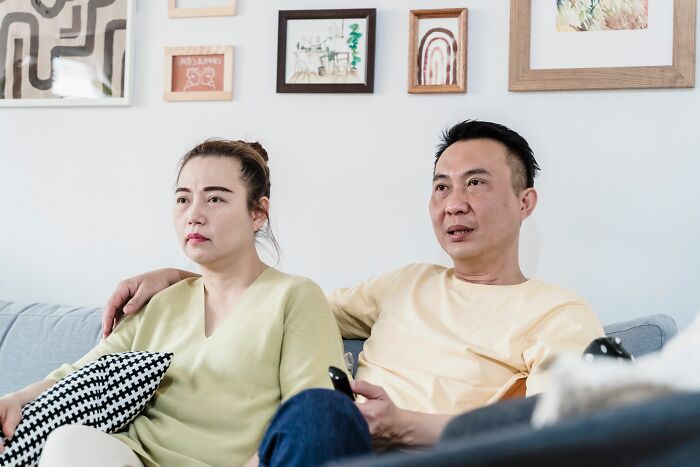 A couple watching TV on a sofa, representing everyday life and things about America.