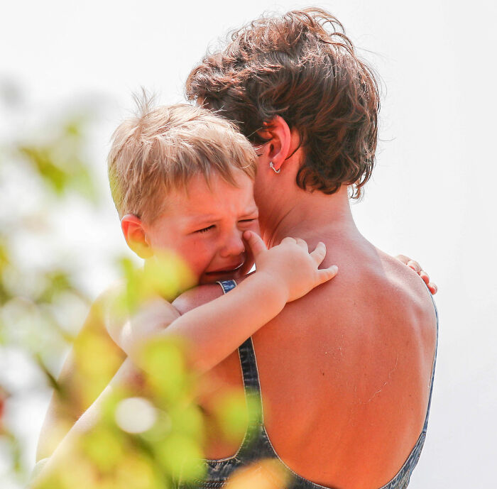 A crying child is comforted by a parent, representing the challenges of having kids that the woman went viral for discussing. A crying child is comforted by a parent, representing the challenges of having kids that the woman went viral for discussing.