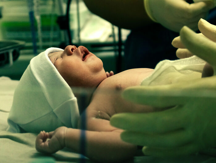 A newborn baby is held by medical professionals after birth, possibly related to a man who married his cousin. A newborn baby is held by medical professionals after birth, possibly related to a man who married his cousin.