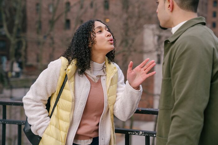 A woman with curly hair passionately arguing with a man outdoors, showing dumb reasons couples divorce.