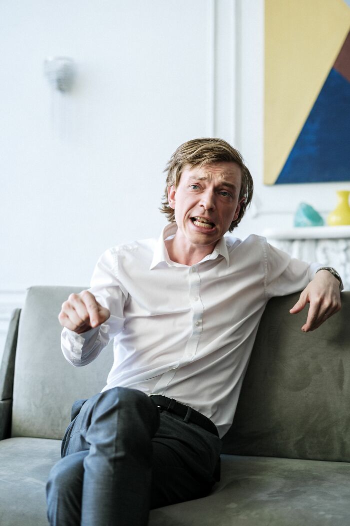 A man on a couch, making a face, demonstrating the delivery of sick burns.