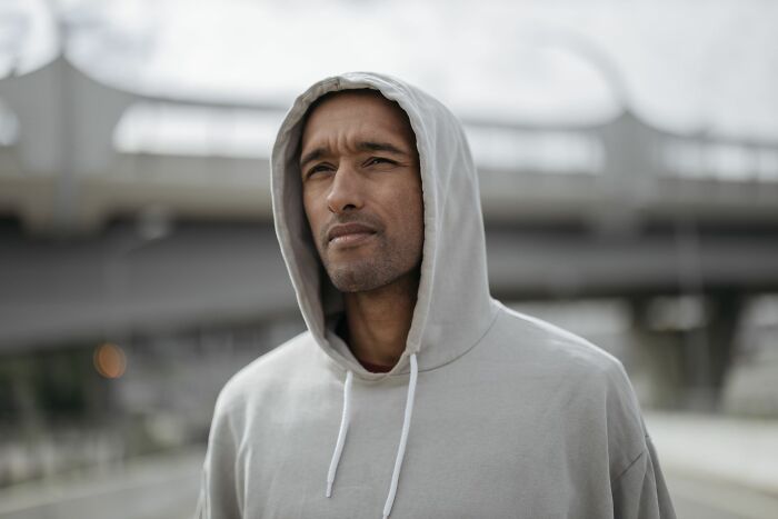 A man in a hoodie looking thoughtfully, representing an employee reflecting on stories that could lead to being fired.