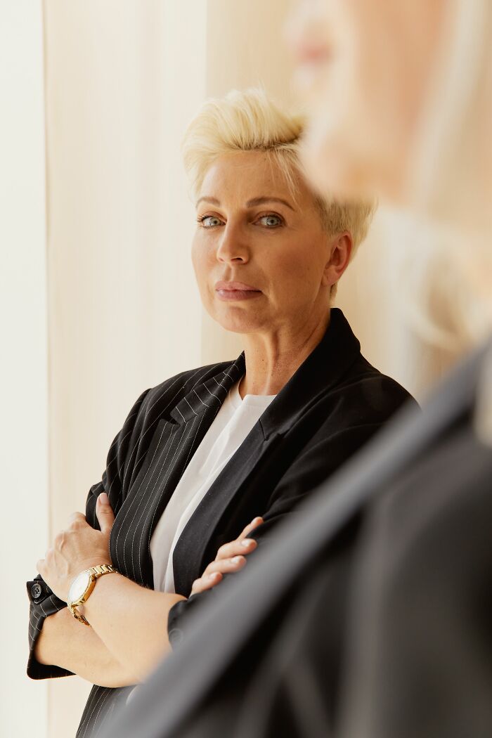 A woman with short blonde hair, arms crossed, exuding the confidence of someone delivering sick burns.