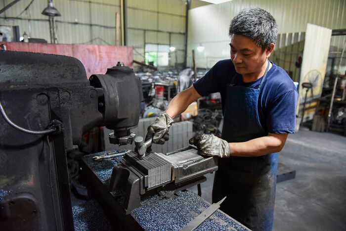 A man in a workshop operates heavy machinery, working with metal in America.