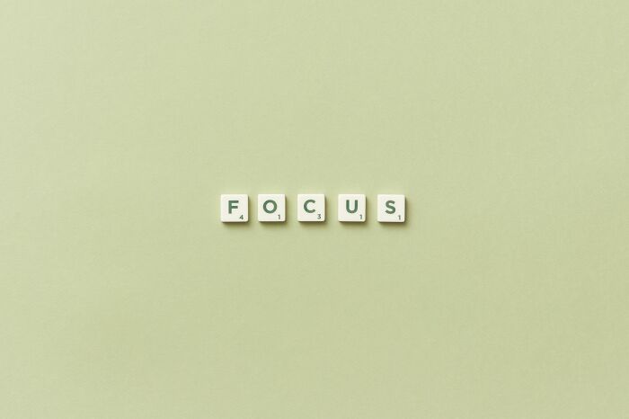 Scrabble tiles spelling FOCUS on a light green background, symbolizing answering questions with five-letter words.