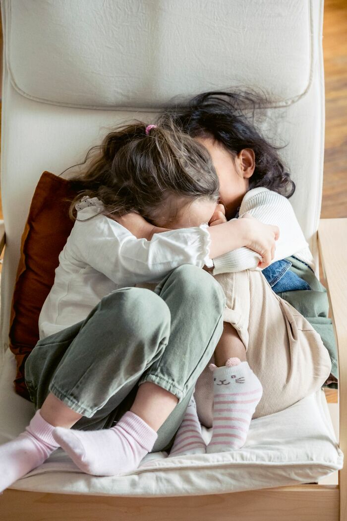 Two girls embracing on a chair, finding comfort after hearing creepy true stories.